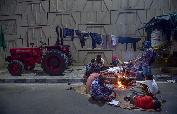 Farmers keep themselves warm around a bonfire during their sit-in protest against the Centre's farm reform laws, near Ghazipur border in New Delhi. Credit: PTI