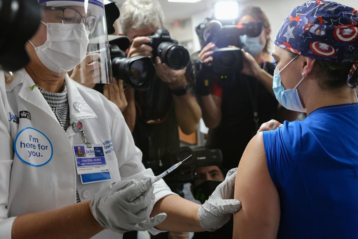 A healthcare worker at Jackson Memorial Hospital recives a Pfizer-BioNtech Covid-19 vaccine from June Ellis at Jackson Memorial Hospital, in Miami, Florida. Credit: AFP