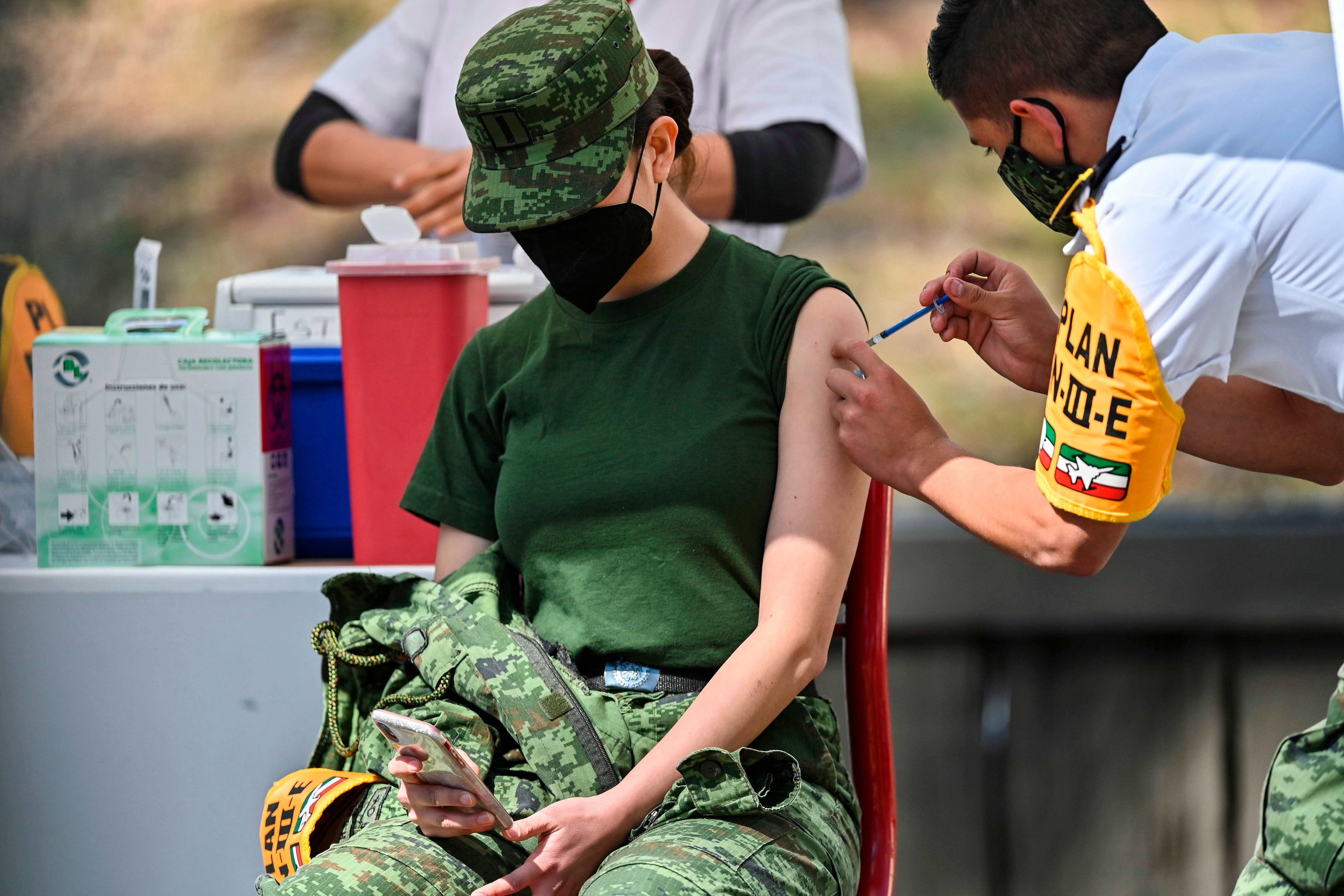 A Mexican military medical receives the Pfizer/BioNTech Covid-19 vaccine jab, at the Military College in Mexico City, on December 27, 2020. - Dozens of nurses and doctors felt they had regained "peace of mind" and strength to continue fighting the COVID-19 pandemic, after being vaccinated against the disease in Mexico. Credit: AFP