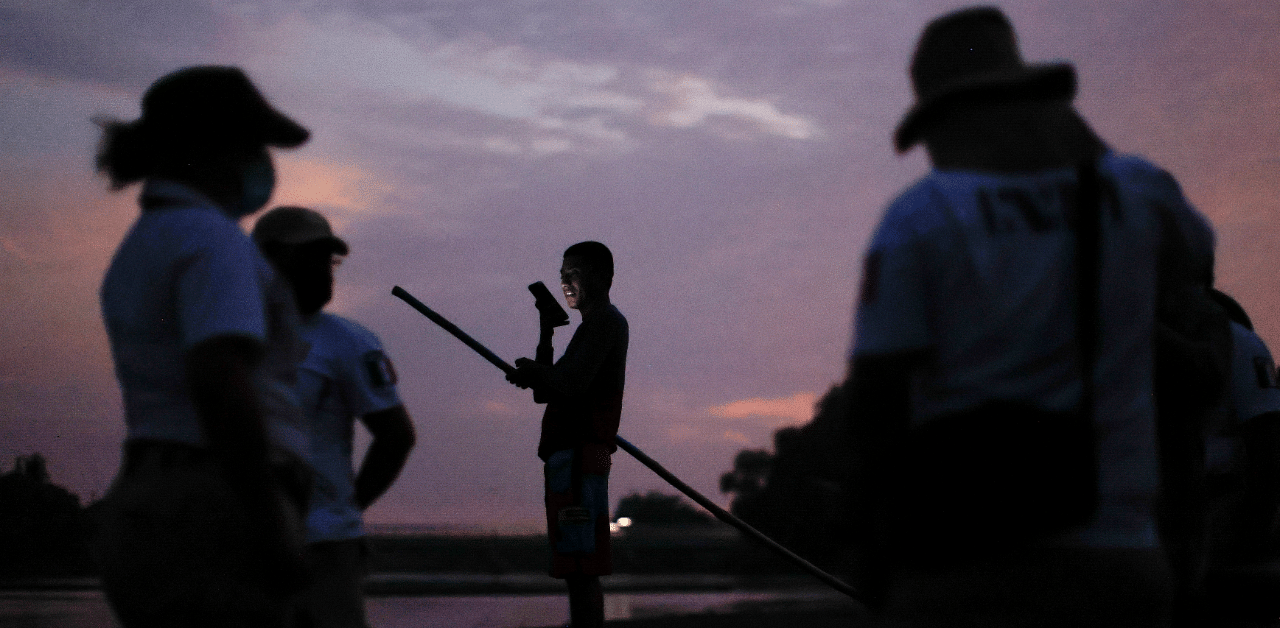 A man holds a mobile phone as immigration agents stand by the bank of the Suchiate River, while they guard the border with the National Guard to prevent a migrant caravan of Central Americans from entering, in Ciudad Hidalgo. Credit: Reuters Photo