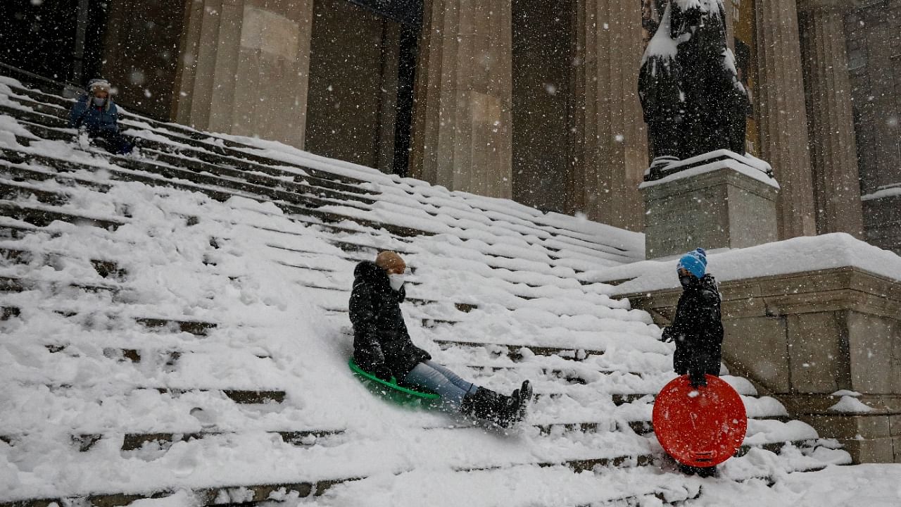 A family sleds on the steps of Federal Hall on Wall St. across from the New York Stock Exchange (NYSE) during a snow storm in the Manhattan borough of New York City. Credit: Reuters Photo
