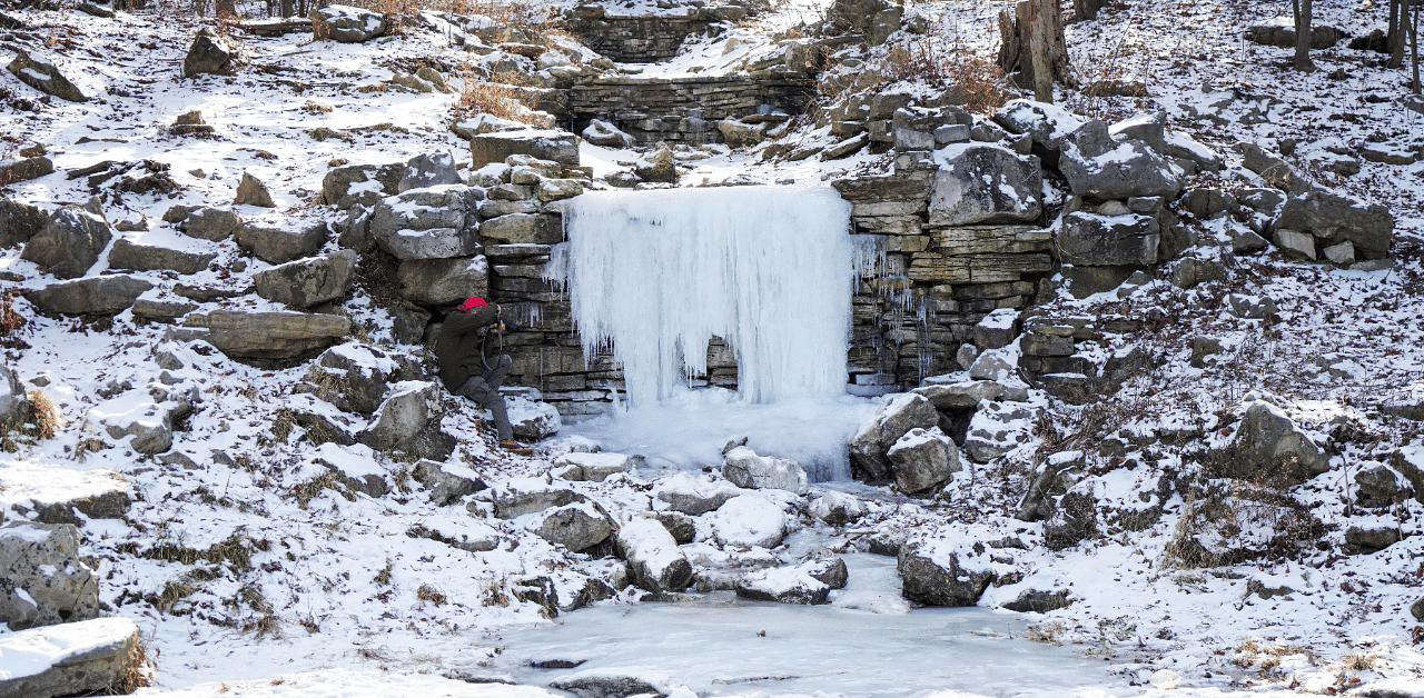 A man takes a photo of a frozen waterfall during cold weather in St Louis, Missouri, US. Credit: Reuters Photo