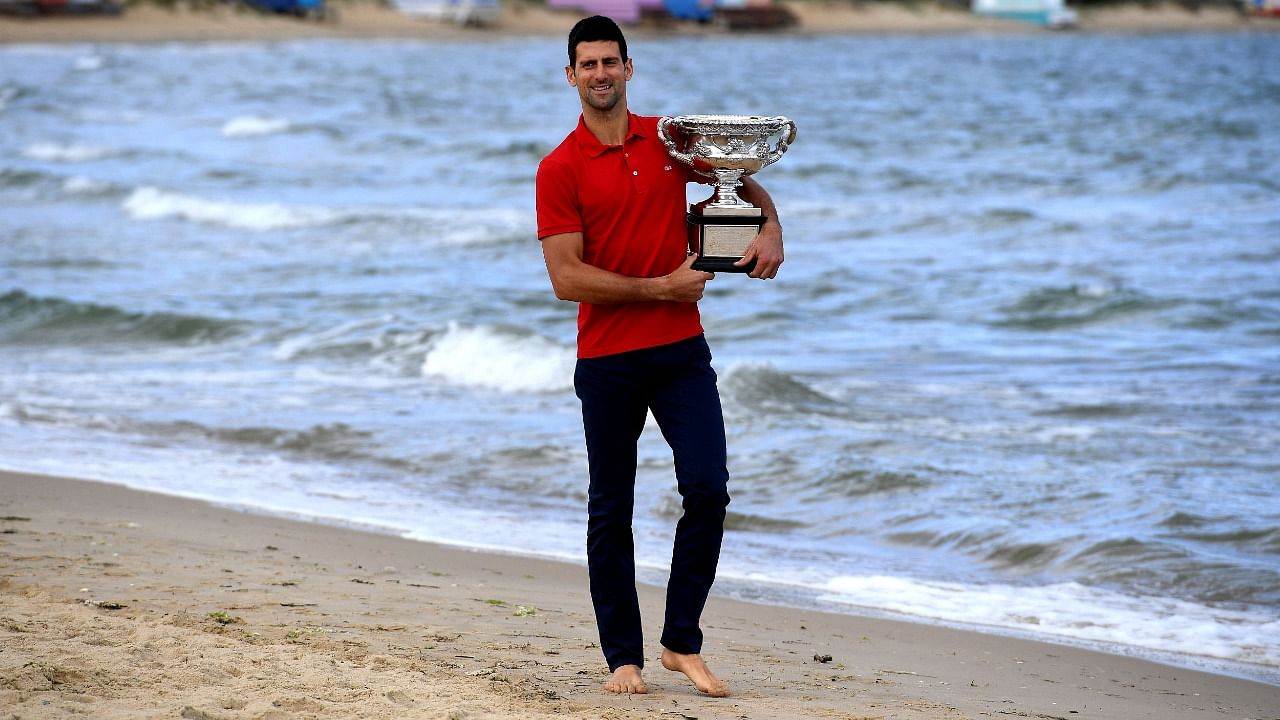 Serbia's Novak Djokovic walks on the Brighton Beach with the Norman Brookes Challenge Cup trophy during a photo shoot in Melbourne on February 22, 2021, a day after his victory over Russia's Daniil Medvedev in their men's singles final match of the Australian Open tennis tournament. Credit: AFP Photo