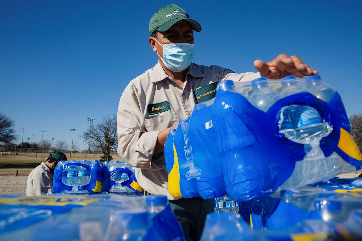 Ramiro Guerra, a Dallas Parks and Recreation employee, picks up a case of water to hand out at a distribution site after winter weather caused electricity blackouts and water service disruption in Dallas, Texas. Credit: Reuters photo. 