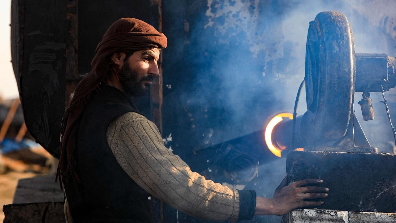 A displaced Syrian man works at a at makeshift oil refinery near the village of Tarhin in an area under the control of Turkish-backed factions in the northern countryside of Aleppo. Credit: AFP Photo