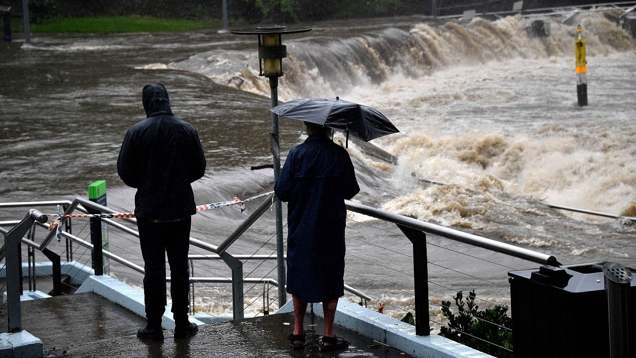 Residents from the neighbourhood watch the over flowing Parramatta river during heavy rain in Sydney on March 20, 2021, amid mass evacuations being ordered in low-lying areas along Australia's east coast as torrential rains caused potentially "life-threatening" floods across a region already soaked by an unusually wet summer. Credit: AFP Photo