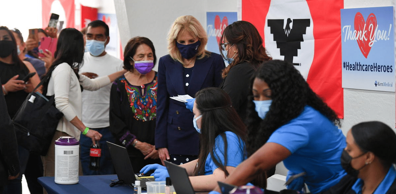 US labour leader and civil rights activist Dolores Huerta (purple mask) stands next to US First Lady Jill Biden as she talks with volunteers at a vaccination site at The Forty Acres, the first headquarters of the United Farm Workers labour union, in Delano, California. Credit: Reuters Photo