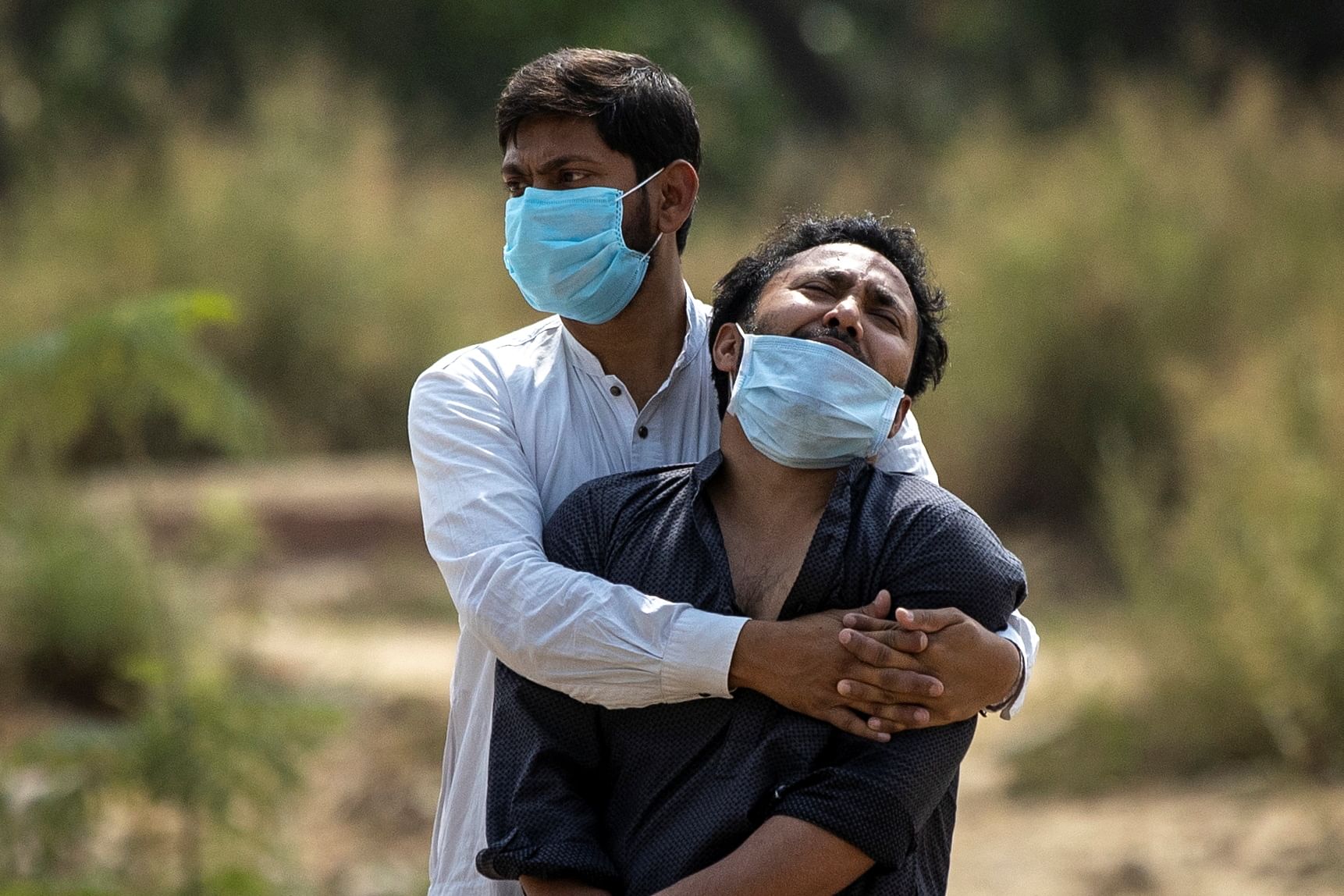 A man is consoled by his relative as he sees the body of his father, who died from the coronavirus disease (Covid-19), before his burial at a graveyard in New Delhi. Credit: Reuters photo