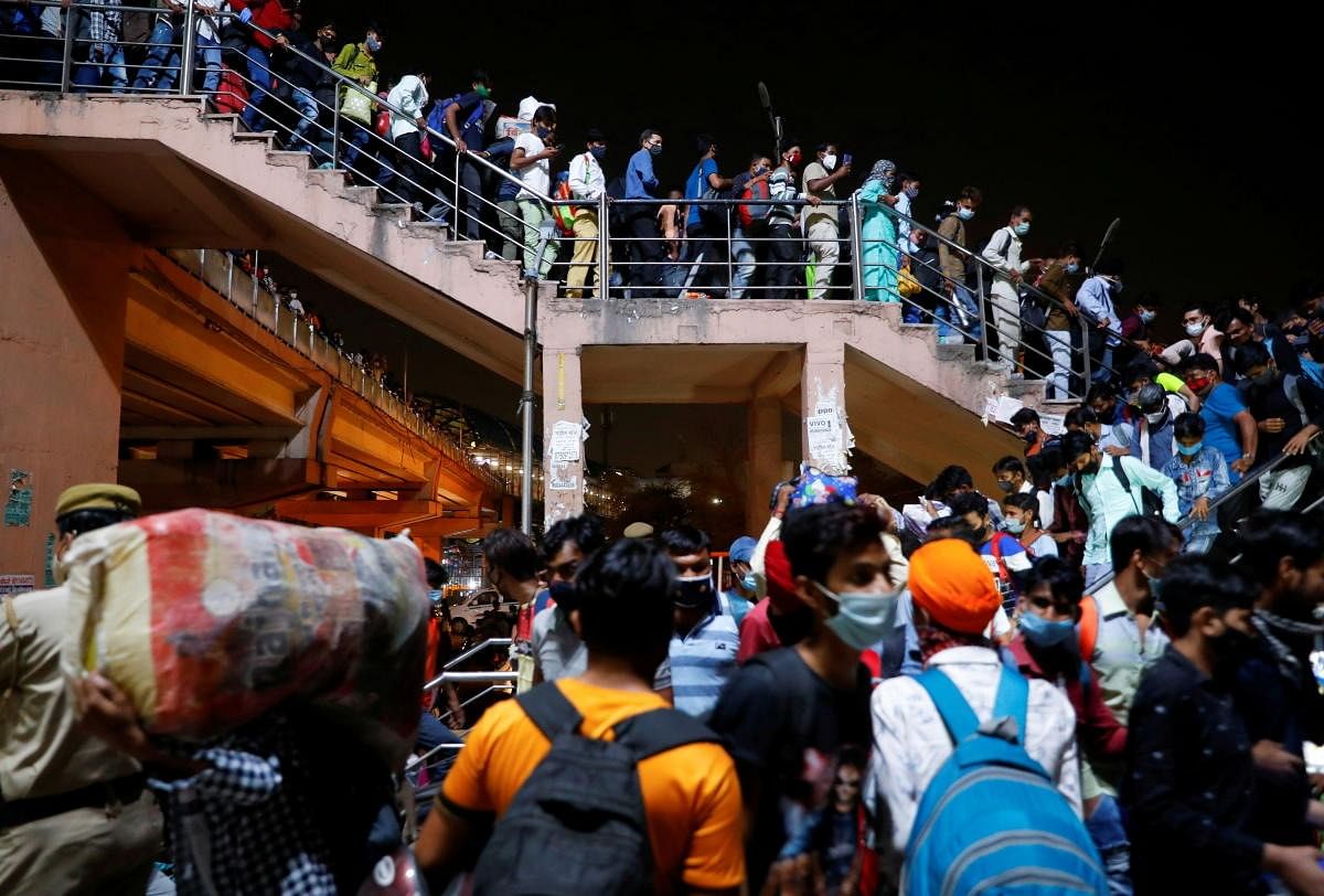 Migrant workers arrive at a bus station to board buses to return to their villages after Delhi government ordered a six-day lockdown to limit the spread of the coronavirus disease (Covid-19), in Ghaziabad. Credit: Reuters Photo