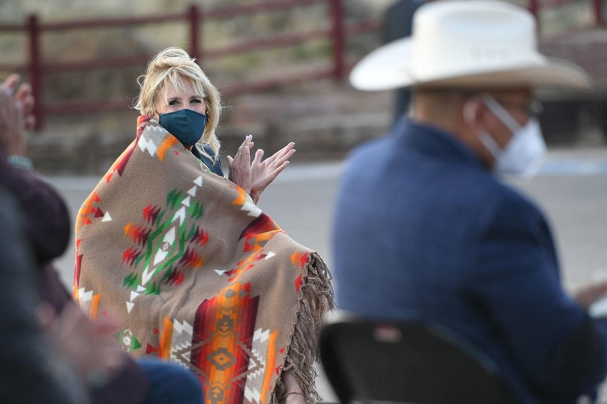 US First Lady Jill Biden, wrapped in a blanket against the chill wind, listens to Navajo Nation President Jonathan Nez (off frame) speak during a live radio address at the Window Rock Navajo Tribal Park & Veterans Memorial in Window Rock, Arizona. Credit: AFP photo.