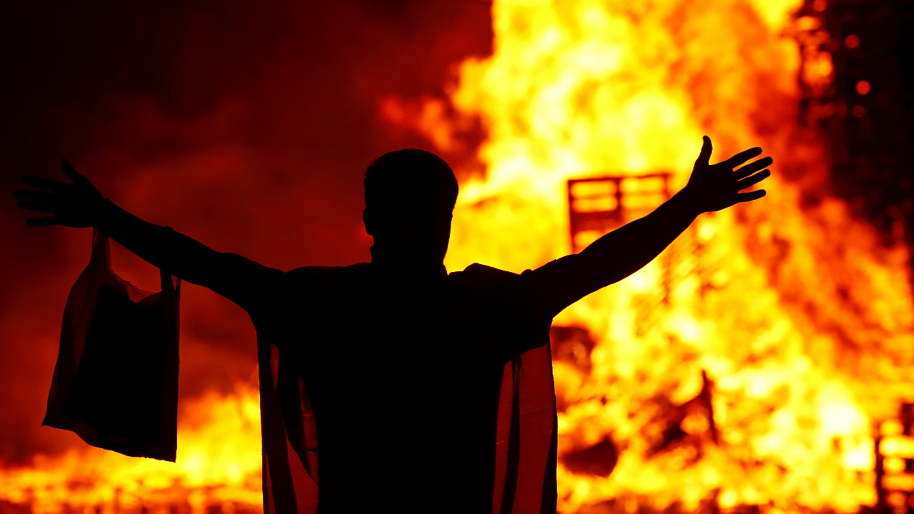 A person gestures in front of the Loyalist Corcrain Redmanville bonfire, which was lit to mark the start of the unionist Twelfth celebrations, in Portadown, Northern Ireland. Credit: Reuters Photo