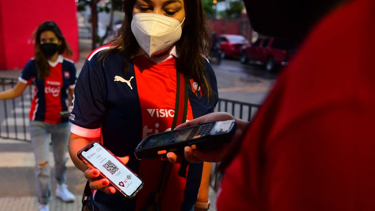 A fan has a QR code checked to control her inoculation and negative test for Covid-19 at the entgrance of the Cerro Porteno stadium before the Clausura tournament football match between Cerro Porteno and Libertad in Asuncion on July 25, 2021. Credit: AFP Photo