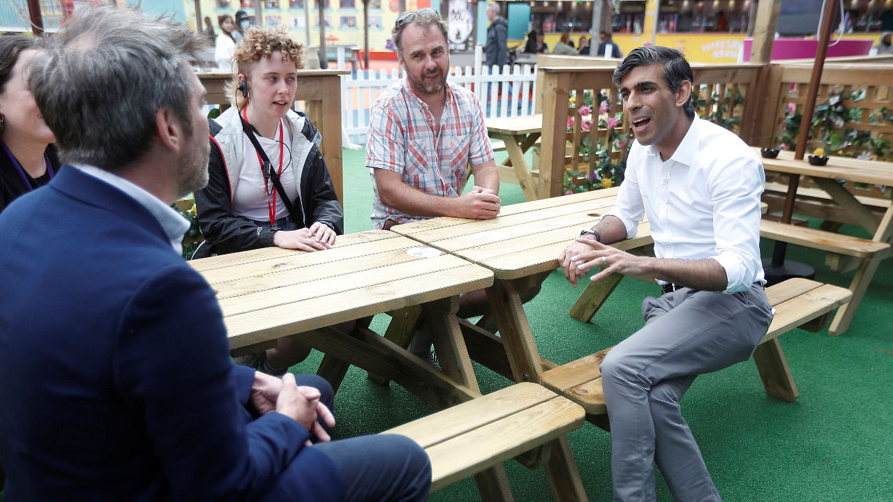 Britain’s Chancellor Rishi Sunak speaks with Ed Bartlam, founder of Underbelly, and previously furloughed staff at the London Wonderground comedy and music festival venue in London. Credit: Reuters Photo
