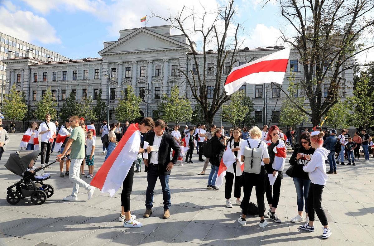 Demonstrators wear Belarusian flags during a rally called "We won't forget, We won't forgive!" in front of the Museum of Occupations and Freedom Fights in Vilnius. Credit: Reuters Photo