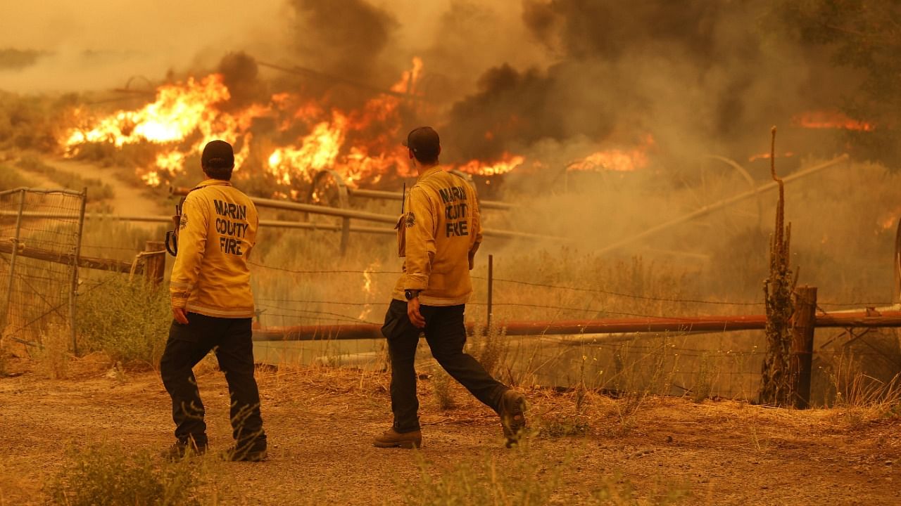 Marin County firefighters survey a spot fire as the Dixie Fire moves through the area near Milford, California. Credit: AFP Photo