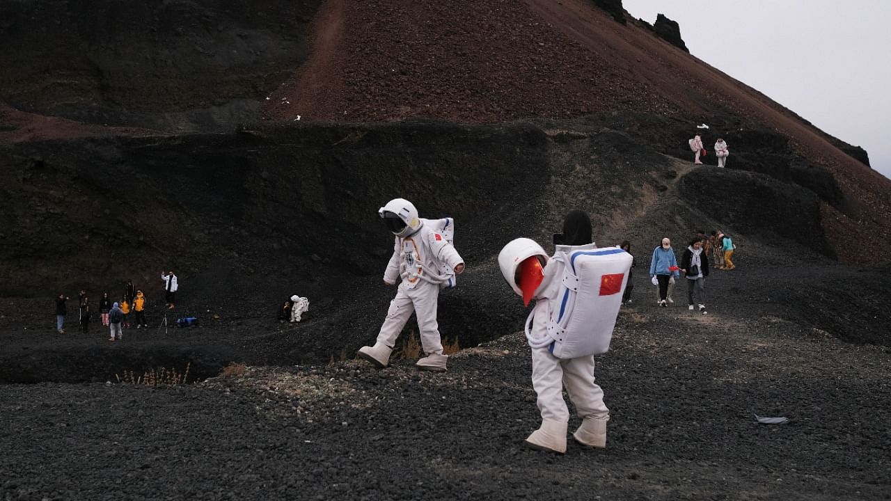 People dressed in astronaut costumes pose for pictures while visiting the Volcano No. 6 of the Ulan Hada volcano group near Ulanqab, Inner Mongolia Autonomous Region, China. Credit: Reuters Photo