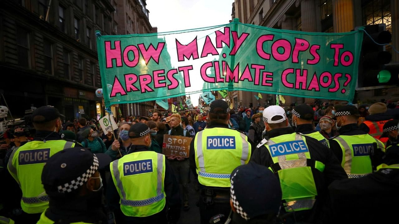 Extinction Rebelion activists stand in front of police officers as they protest during the UN Climate Change Conference (COP26) in Glasgow, Scotland. Credit: Reuters photo