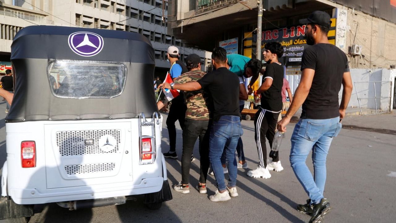 Supporters of Iraqi Shiite armed groups carry an injured man after clashes with security forces during a protest against the election results in Baghdad. Credit: Reuters photo