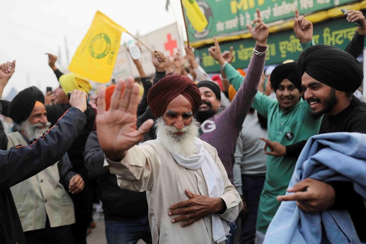 Farmers celebrate after Prime Minister Narendra Modi announced that he will repeal the controversial farm laws, at the Singhu border farmers protest site near Delhi-Haryana border. Credit: Reuters Photo