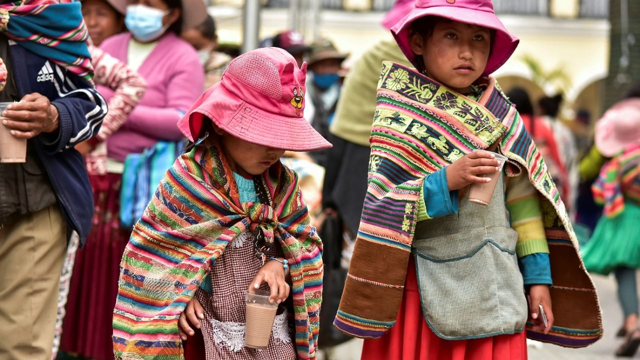 Girls hold plastic cups with hot chocolate after volunteers handed out sweets and toys to families coming from the countryside to take part in Christmas celebrations, in Cochabamba, Bolivia. Credit: Reuters Photo