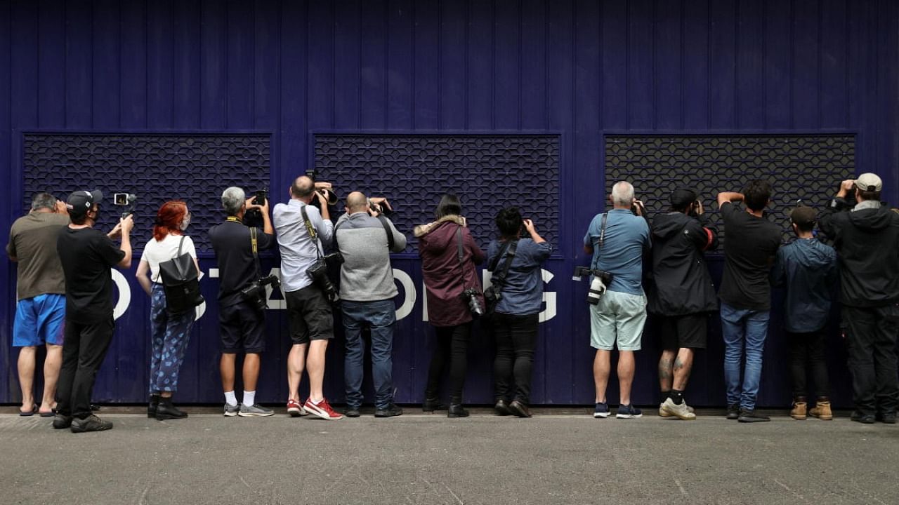 Photographers and videographers peer into a car park trying to get a glimpse of Serbian tennis player Novak Djokovic at the offices of his legal team, after the athlete's visa to play in the Australian Open was cancelled a second time, in Melbourne, Australia, January 15, 2022. Credit: Reuters Photo