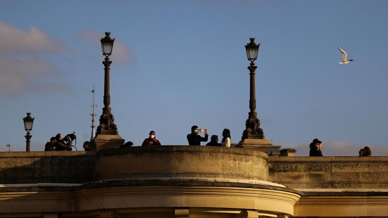 People stand on a bridge over the Seine river, amid the Covid-19 pandemic, in Paris. Credit: Reuters photo