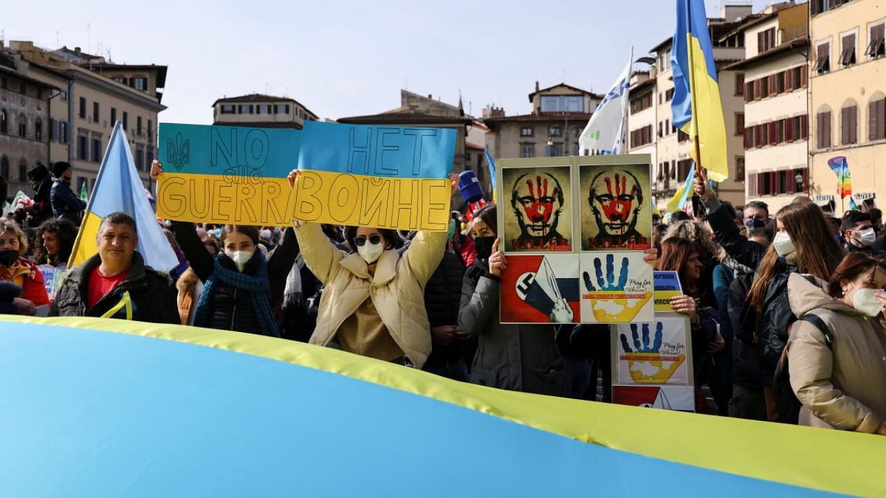 Demonstrators hold signs as they gather in Santa Croce square to protest against the Russian invasion of Ukraine, in Florence. Credit: Reuters photo