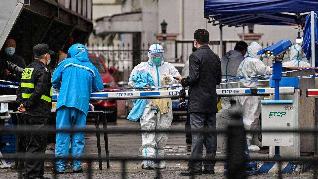 A delivery man (L in blue) is seen arriving to deliver an order outside of a locked down neighbourhood after the detection of new cases of Covid-19 in Huangpu district, in Shanghai. Credit: AFP Photo