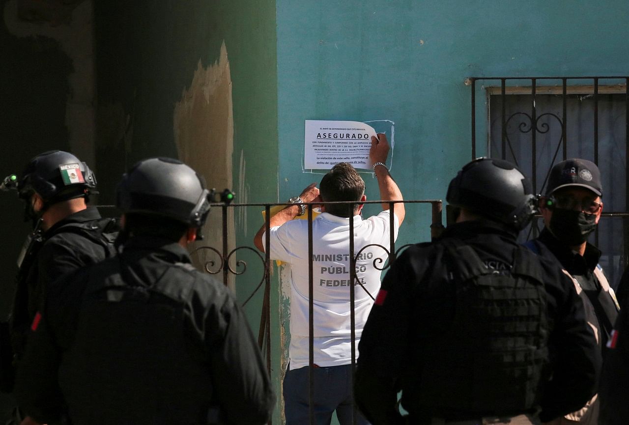 A prosecutor representative put a notice saying "Insured" as members of the Attorney General's Office look on outside a house where a drug trafficking tunnel was discovered that goes under the US-Mexico border. Credit: Reuters Photo