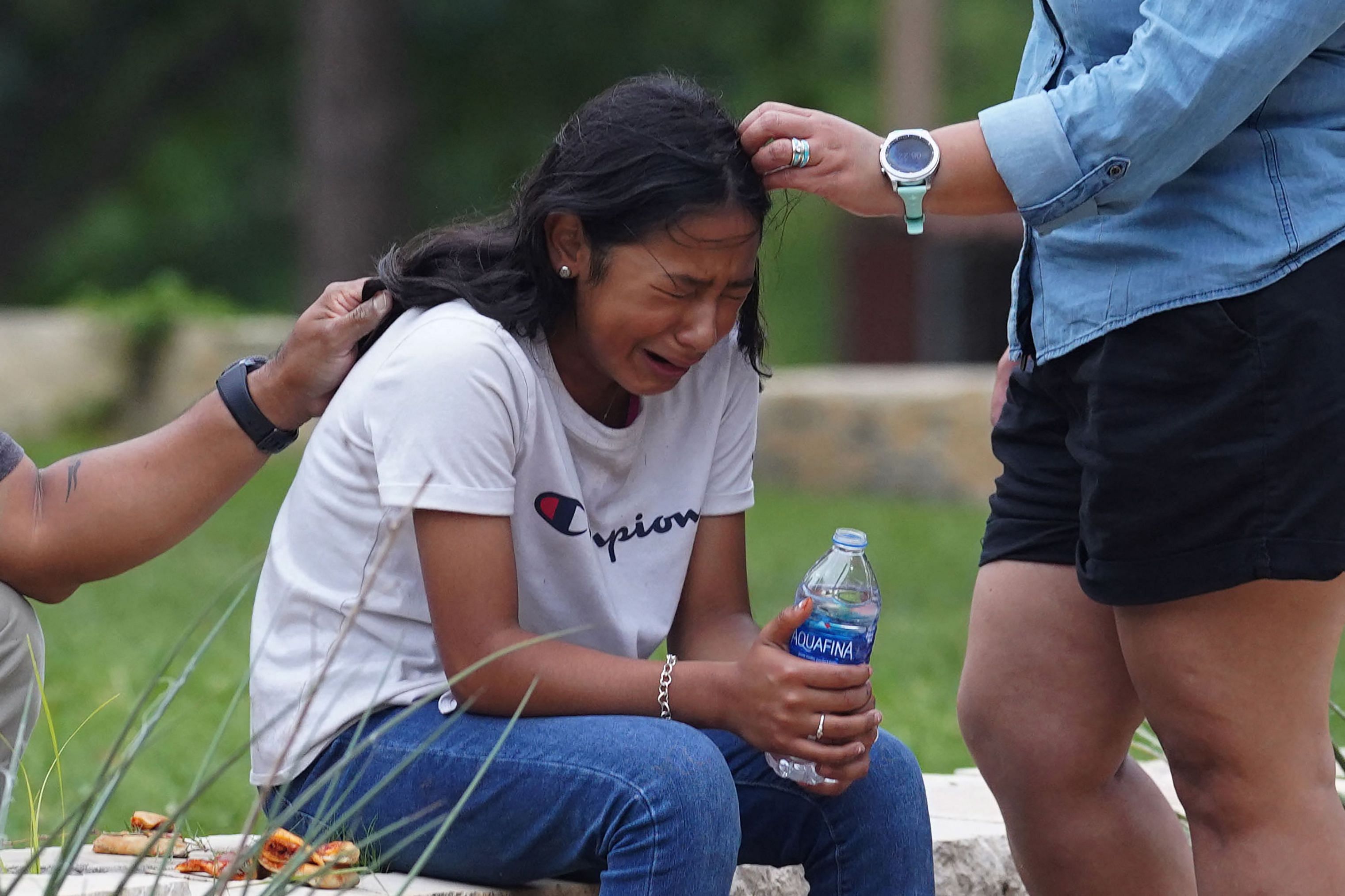 A girl cries, comforted by two adults, outside the Willie de Leon Civic Center where grief counseling will be offered in Uvalde, Texas. Credit: AFP Photo