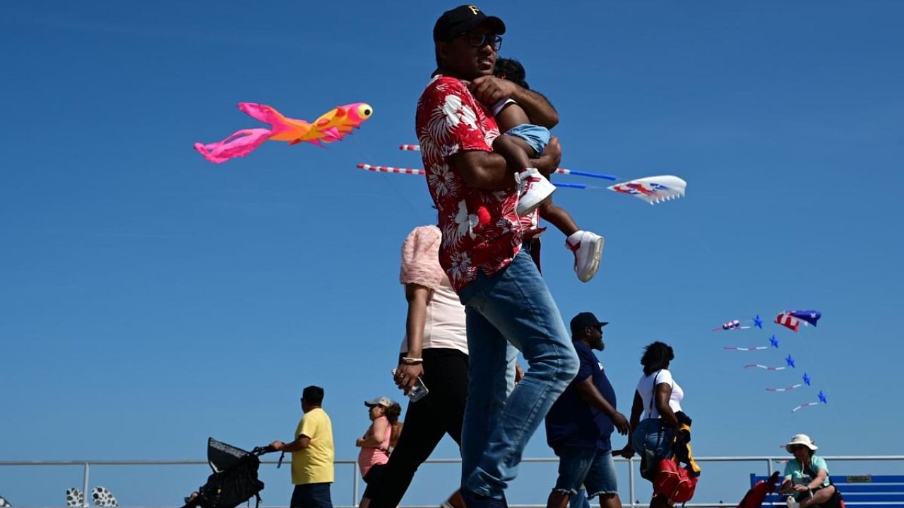 People walk the boardwalk as kites fly from the beach in the background on May 30, 2022 in Wildwood, New Jersey.