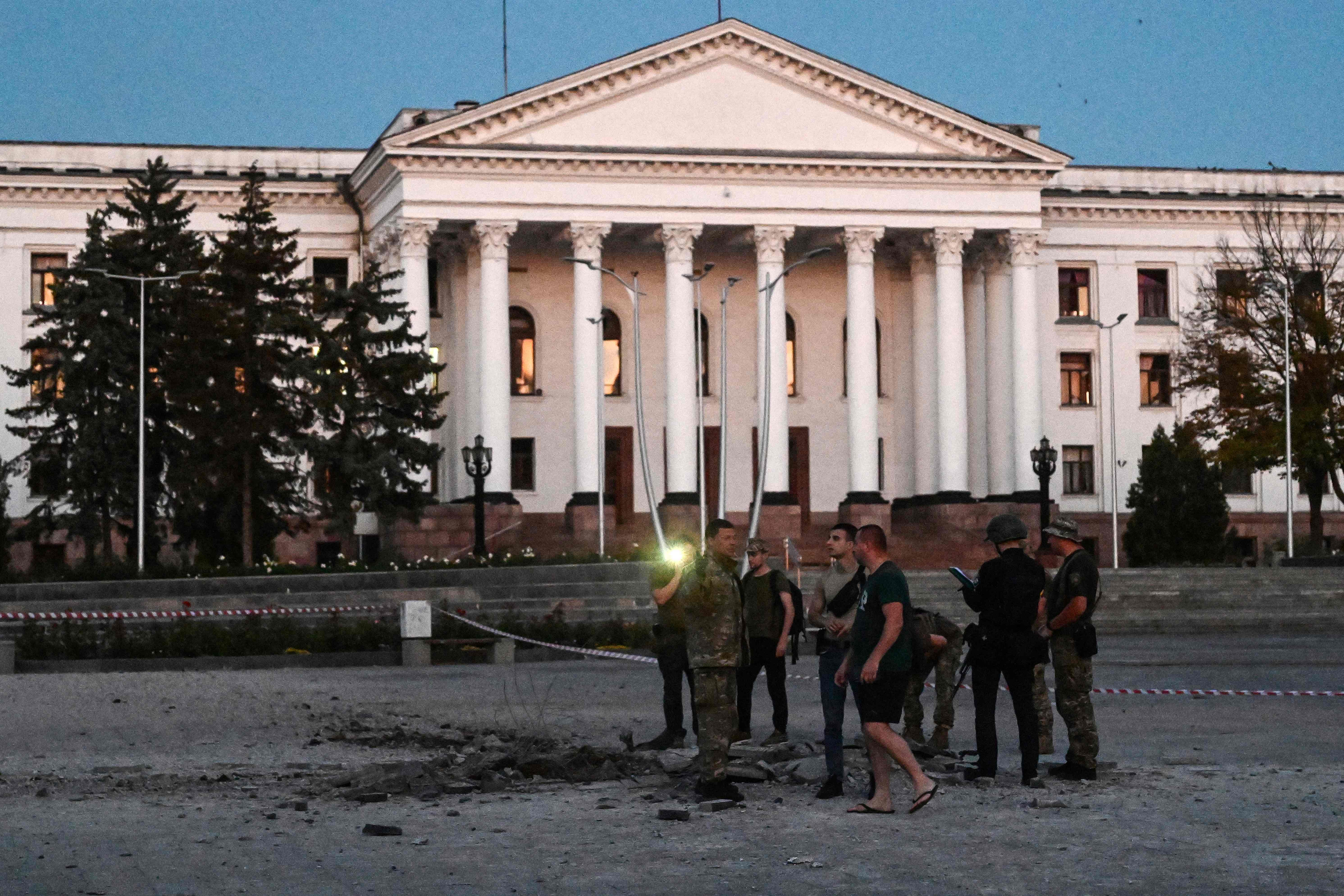 Ukrainian servicemen inspect the damaged ground of a street after an air strike hit the Myru (Peace) square in front of the Palace of Culture and Technology and the City Hall in the center of Kramatorsk on July 15, 2022, amid the Russian invasion of Ukraine.