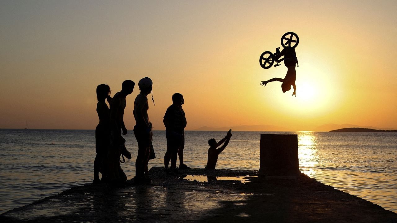 A biker performs tricks at Kavouri beach during a heatwave near Athens, Greece. Credit: Reuters photo