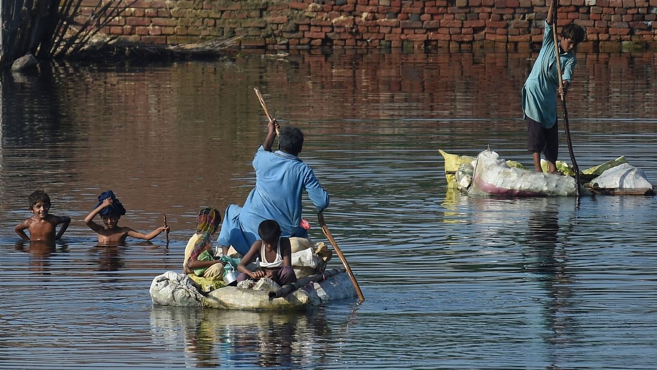 People use rafts to cross a flooded area after monsoon rains on the outskirts of Sukkur, Sindh province, on September 1, 2022. - Monsoon rains have submerged a third of Pakistan, claiming at least 1,190 lives. Credit: AFP Photo