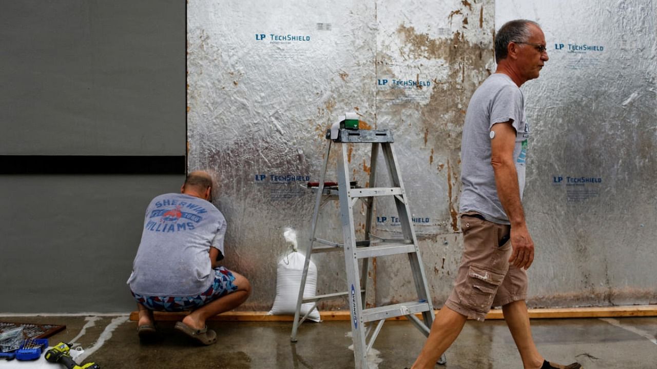 Men work boarding up a shop window as Hurricane Ian spins toward the state carrying high winds, torrential rains and a powerful storm surge, in Port Charlotte, Florida. Credit: Reuters photo
