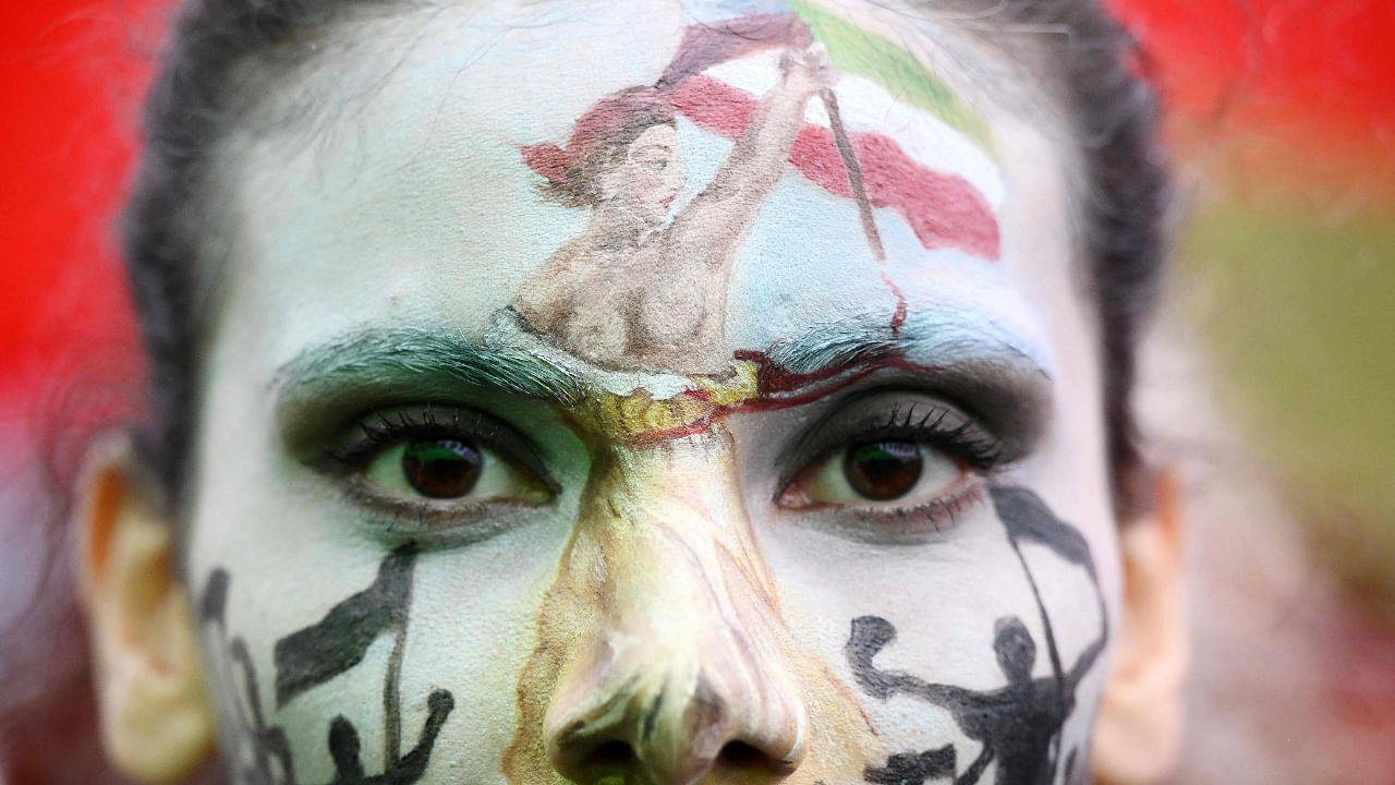 A protester wearing face-paint depicting France's iconic "Marianne" leading an uprising, attends a demonstration in support of Kurdish woman Mahsa Amini during a protest on October 2, 2022 on Place de la Republique in Paris, following her death in Iran. Credit: AFP Photo