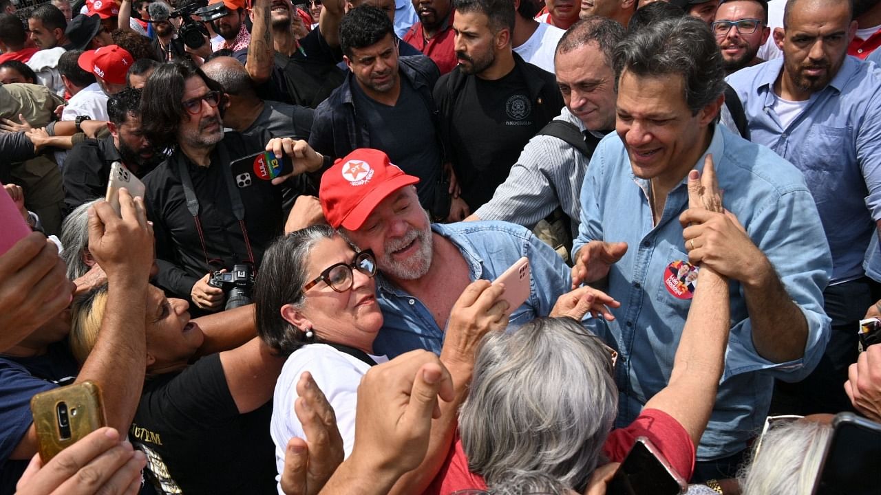 Brazilian former President (2003-2010) and candidate for the leftist Workers Party (PT), Luiz Inacio Lula da Silva (C), and Sao Paulo Governor candidate Fernando Haddad (R) greet supporters during a campaign rally in Sao Bernardo do Campo, Brazil, on October 6, 2022. Credit: AFP Photo