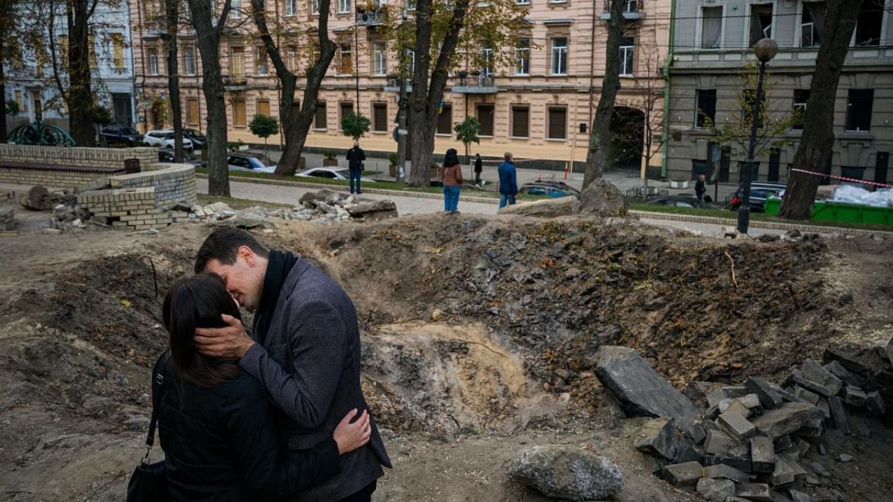 A couple kiss by a rocket crater in a park of central Kyiv on October 12, 2022, two days after Ukraine's capital was hit by multiple Russian strikes, the first since late June. Credit: AFP Photo