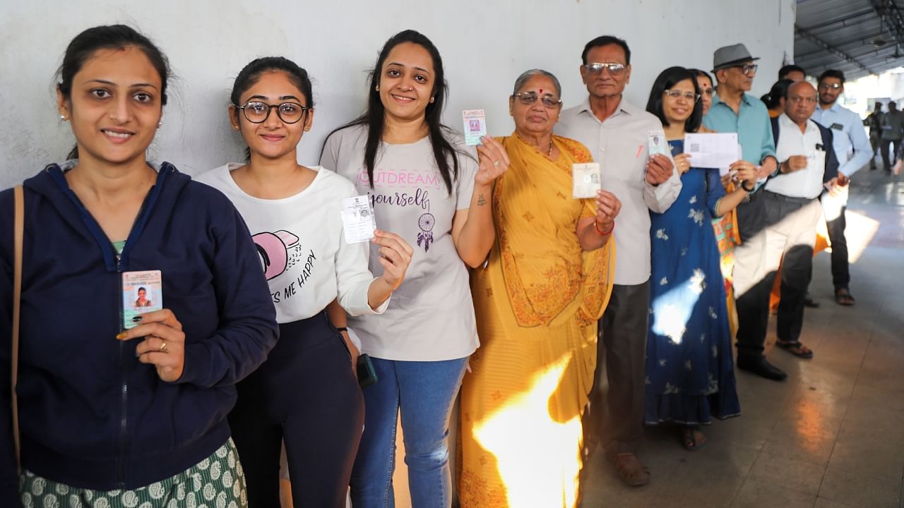 People show their identification cards as they wait in a queue to cast their votes in Rajkot. Credit: PTI Photo