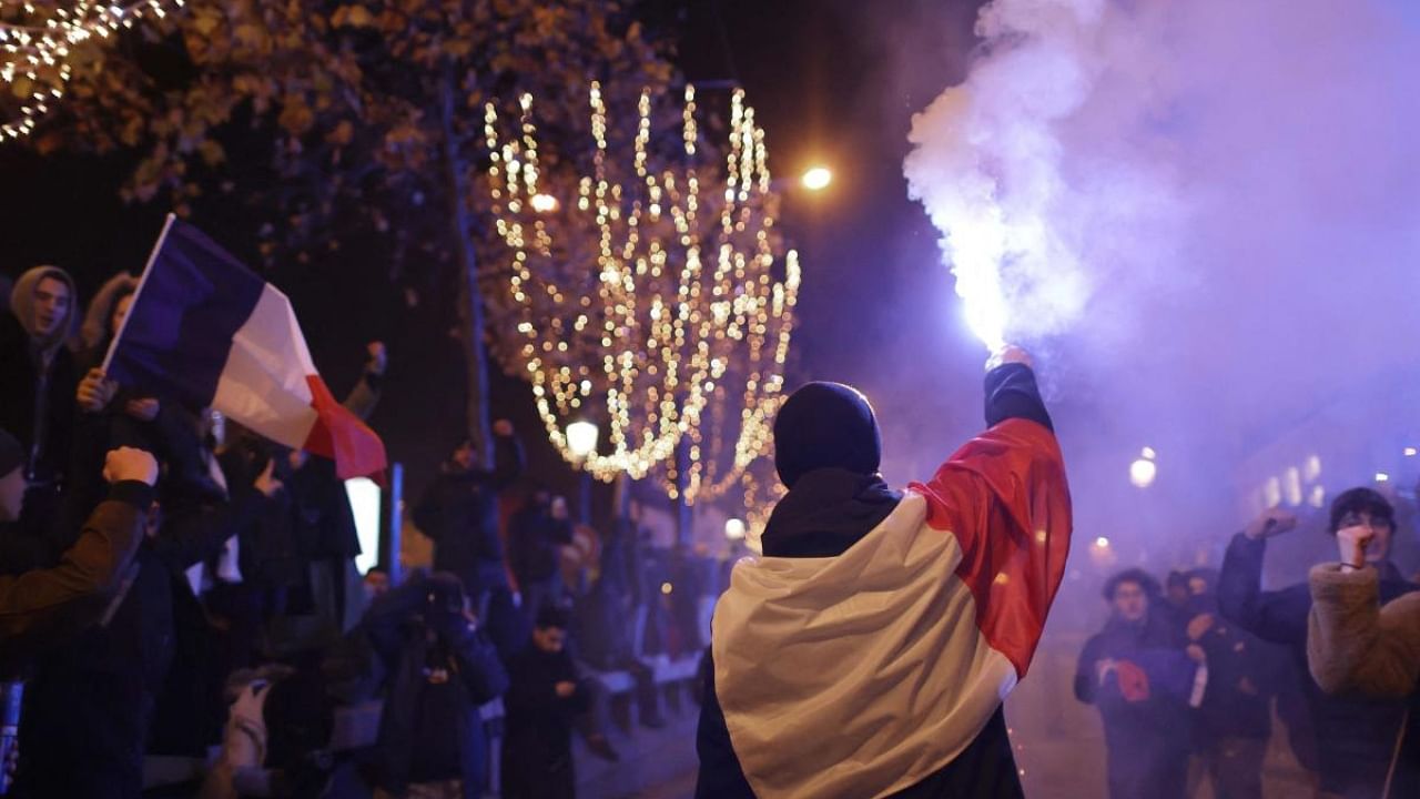 A France's supporter holds a smoke flare after France's victory over Morocco in the Qatar 2022 World Cup semi-final on the Champs-Elysees in Paris. Credit: AFP Photo
