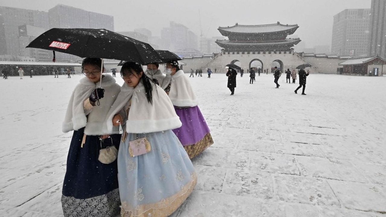Visitors wearing traditional hanbok dress walk through Gyeongbokgung palace during snowfall in central Seoul. Credit: AFP Photo