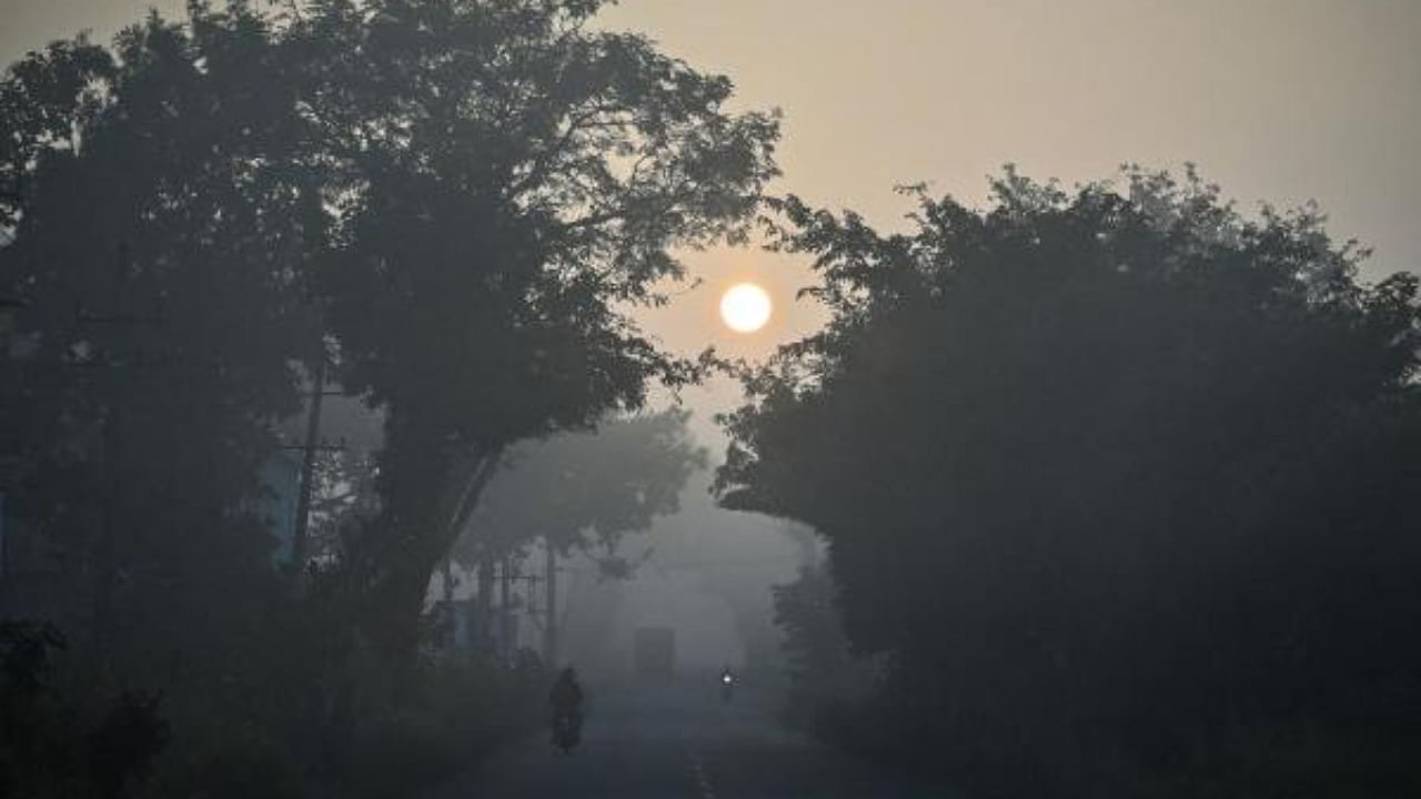 Commuters make their way along a road amid dense fog on a cold winter morning in Bengaluru. Credit: AFP Photo