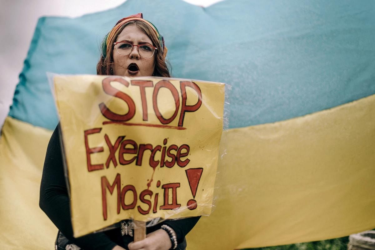 A protester holds a slogan in front of a Ukraine's flag during a demonstration at Umhlanga beach in Durban against South Africa's joint military exercise with Russia and China along its eastern coast city of Richards Bay. Photo Credit: AFP Photo