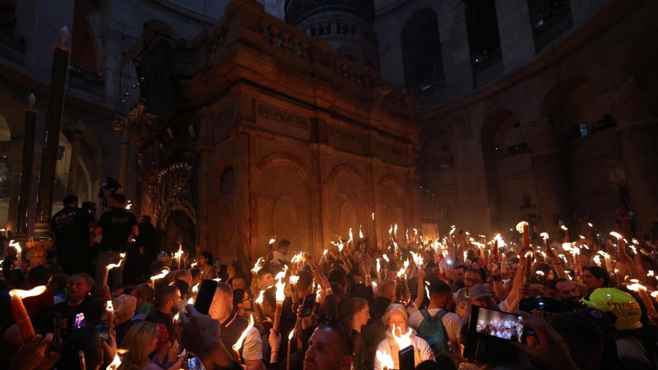 Orthodox Christians gather with lit candles around the Edicule, traditionally believed to be the burial site of Jesus Christ, during the Holy Fire ceremony at the Holy Sepulchre church in Jerusalem's Old City on April 15, 2023 on the eve of Easter Sunday. Credit: AFP Photo